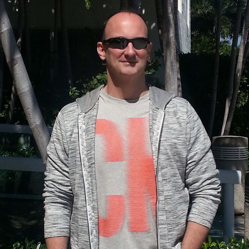 Abstract acrylic painter Geoff Swetz standing outdoors in sunglasses and a gray hoodie